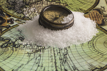 Antique compass on white ice floes on a world map background.