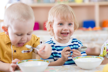 Obraz na płótnie Canvas Funny smiling little kid eating in kindergarten