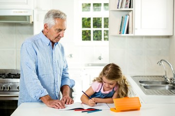Obraz premium Girl studying at table with granddad 
