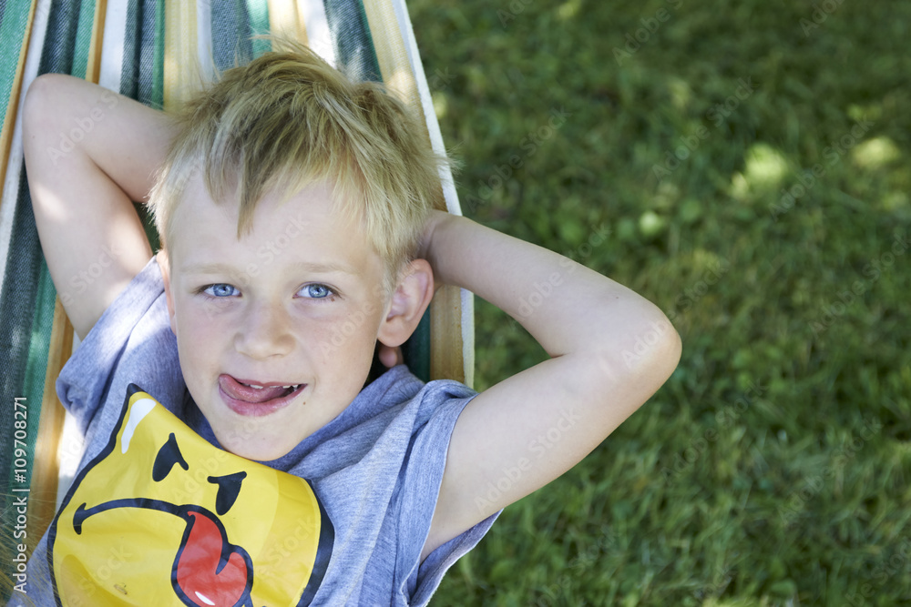 Wall mural little cute boy swinging and relaxing on a hammock, summertime, holydays