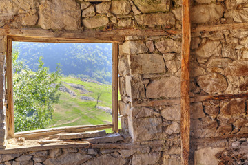 Look through window from abandoned stone house in the mountain