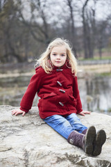 Fototapeta premium A cute five year old blond girl posing on a rock outside 