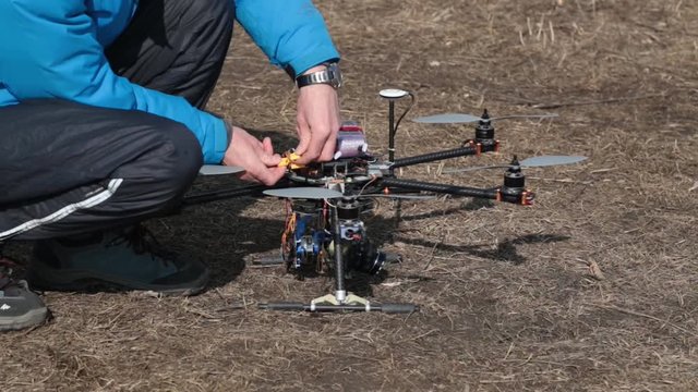 Man connects the battery pack to the quadrocopters