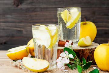 
detox , healthy and refreshing drink ,Nutritious cold sparkling water with fresh apple and cinnamon on a wooden background