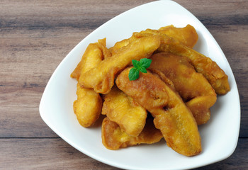 Close up of banana fritters in a plate on wooden table