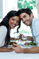 Portrait of couple holding hands while having meal