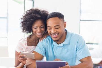 Happy couple using mobile phone and digital tablet