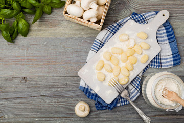 Uncooked homemade potato gnocchi with tomatoes or mushrooms with