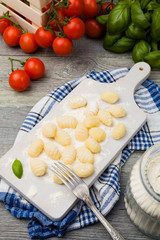 Uncooked homemade potato gnocchi with tomatoes or mushrooms with