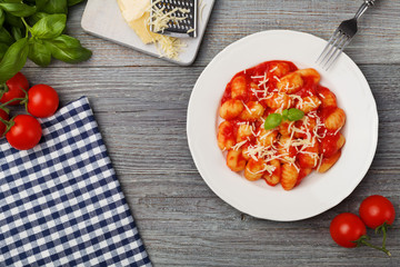 Serving gnocchi in tomato sauce with cheese.