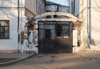 Fototapeta na wymiar Large black metal gate in the arch of the old brick house