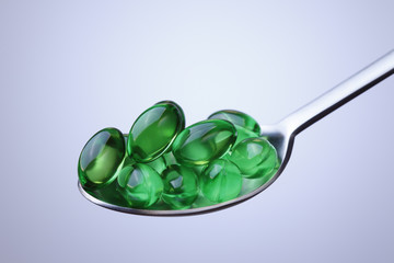 Green nutritional supplement pills in a spoon