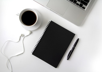 Creative flat lay photo of workspace desk with laptop, earphone, pen, coffee and blank black notebook with copy space background, minimal style