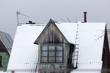 Snow on the roof of the house in the winter