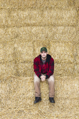 Naklejka na ściany i meble man sitting on bales of hay