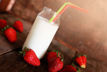 wooden table with strawberries and milk in a glass
