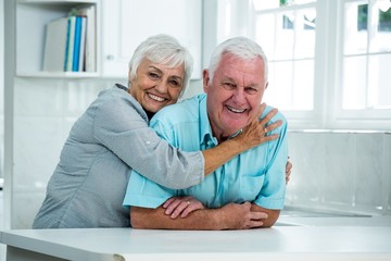 Happy senior woman embracing man at home