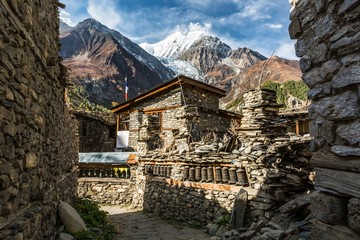 Traditional stone build village of Manang. Mountains in the background. - obrazy, fototapety, plakaty