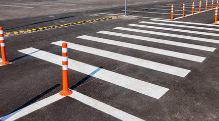 White traffic markings with a pedestrian crossing on a gray asph