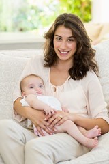 Fototapeta na wymiar Mother holding her baby on lap in living room