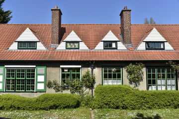 L'une des habitations jumelées typiquement anglais avec lucarnes triangulaires et chassis noirs-verts entouré de verdure à la Cité-Jardin du Logis à Watermael-Boitsfort 