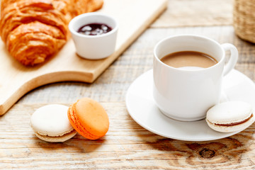 sweet breakfast with coffee, macaroons and croissants on wooden table