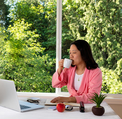 Mature woman enjoying her coffee in the morning while working 