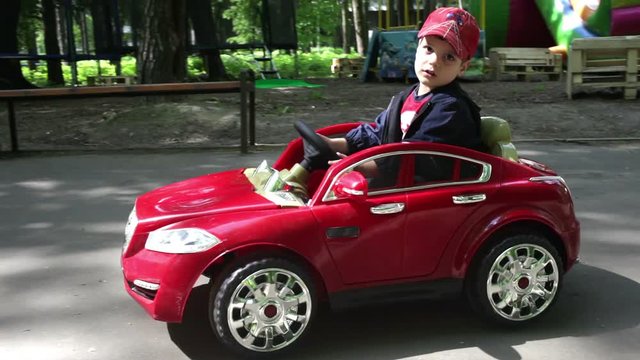 boy rides a red car