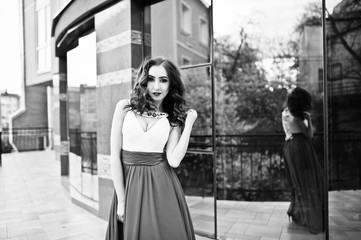 Portrait of fashionable girl at red evening dress posed backgrou
