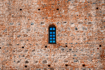 Fototapeta na wymiar Arched window in a aged red brick castle wall