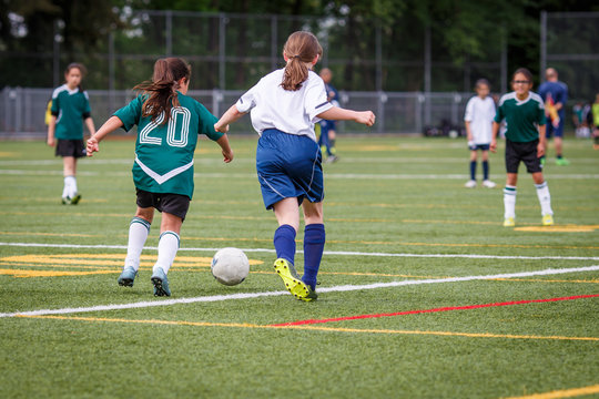 Fototapeta Girls playing soccer at the artificial turf field