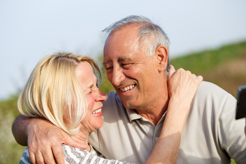 Fototapeta premium Senior couple embracing each other in countryside and and make selfie with phone.