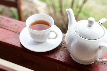 Cup of black tea and kettle on veranda
