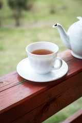 Cup of black tea and kettle on veranda