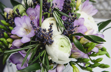 Naklejka premium Beautiful spring bouquet wedding flowers buttercup ranunculus, fresia, lavender nature background. Pastel colors purple, green. Still life concept. Rustic style.