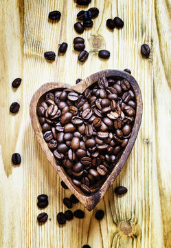 Arabica Coffee beans in a wooden bowl in the shape of a heart, a