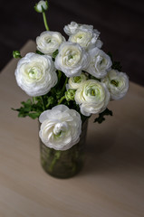 Bouquet white buttercup ranunculus bouquet of flowers in glass vase on a wood table. Still life, rustic style, dark tones.