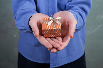 Boy's hand holding a small gift box with polka dots