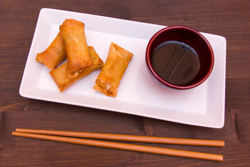 Tray with spring rolls on a wooden table seen from above