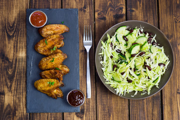 Chicken wings on a slate plate and salad 