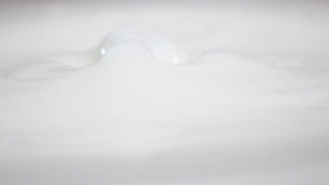 The half of juicy orange drops in fresh white milk with stunning splash in slow motion. Camera horizontal shooting with 500 frames per second speed. 