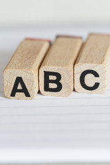 wooden letter stamps with the letters A, B, and C on paper with lines