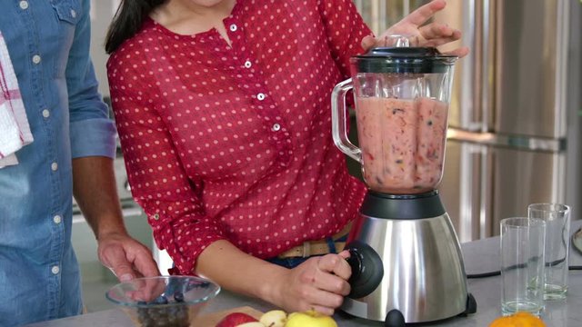 Couple preparing fruit juice on the kitchen