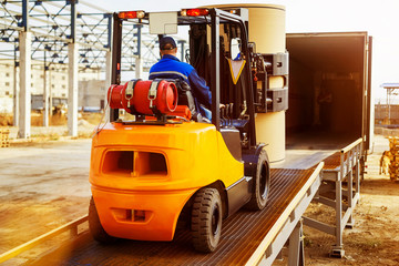 Forklift is putting cargo from warehouse to truck outdoors