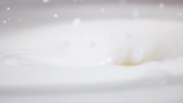 The half of juicy orange drops in fresh white milk with beautiful splash in slow motion and floats. Sony rx 10 ii high-speed shooting.