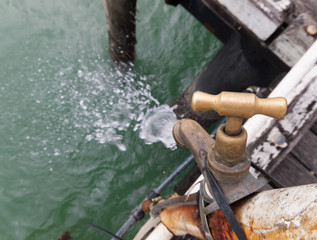 A leaking old rusty tap at a fishing cleaning station on a fishing jetty