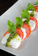Caprese Salad,Vine ripeTomato and Mozzarella slices with basil leaves and fresh green pesto.