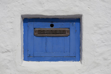 old, wooden, blue painted letter box in a white wall in Sitges, Spain, "Carta" is letter in Spanish