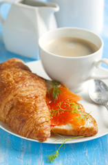 Croissant with salmon and cup of coffee.