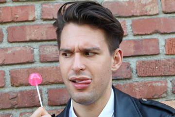 Silly man licks his lollipop in this funny childish photo